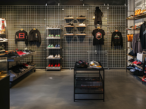 An image of a retail store with black shirts and shoes displayed on white wire grid