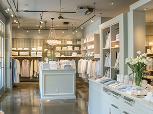 An image of a retail store with white dresses and shirts displayed on wire grid shelving
