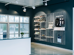 An image of a retail store front desk in front of large windows, with white wire grid panels on a nearby wall